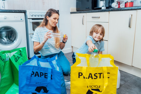 Mother is teaching kid how to recycle help the boy aware environmental importance - mom educates son sort garbage into different bins on kitchen. Family sorting garbage at home. Concept of recycling.の写真素材