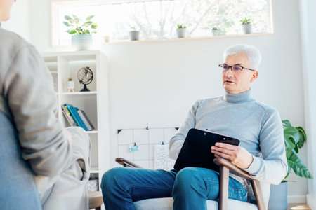 Professional psychotherapy. Male psychologist having session with male patient at mental health clinic, Taking Notes During Appointment In Office. Psychological help service. Treatment of depressionの写真素材
