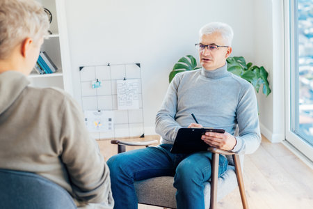Professional psychotherapy. Male psychologist having session with male patient at mental health clinic, Taking Notes During Appointment In Office. Psychological help service. Treatment of depressionの写真素材