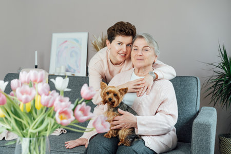 Portrait of happy senior 70s mother, adult neutral gender daughter and Yorkshire terriers dog...