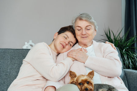 Smiling neutral gender woman and senior mother hugging, elderly mother and adult daughter enjoying...