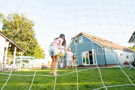 Young mother and son giving five during soccer game in the garden. Happy family playing football,...