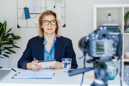 50s confident mature businesswoman, middle-aged experienced senior female professional recording video vlog webinar, online course. Female edtech entrepreneur shares skills, blogger online businessの写真素材