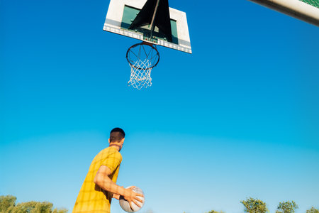 Young Man with basketball ball under hoop, Playing Basketball at Park outdoor playground in sunset...