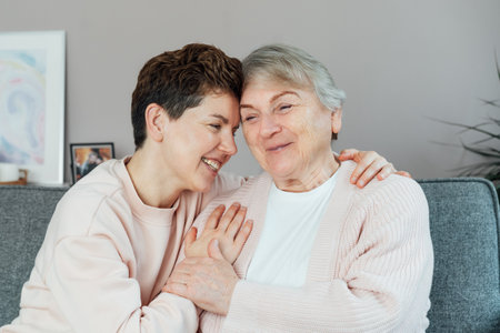 Neutral gender woman hugging her senior mom or grandma, sharing a tender moment together. Parenting love, care and generations unity concept. Mothers day. Happy family enjoying weekend together.の写真素材