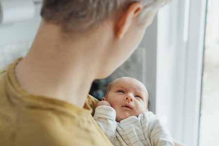 Close up portrait of newborn baby looking with attention at his father. No face dad holding his...