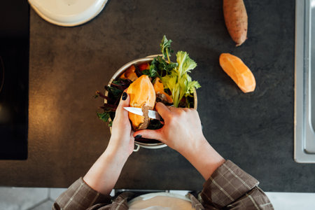Compost the kitchen waste, recycling at home. Woman putting vegetables cutted leftovers into the...