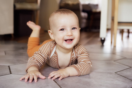 Happy, laughing baby lying on tiled floor at home for child development, wellness and growth....
