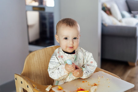 Cute baby learning to eat food with baby spoon by himself on high chair baby led weaning or blw....