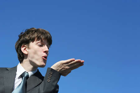 young businessman showing something or blowing on his handの写真素材