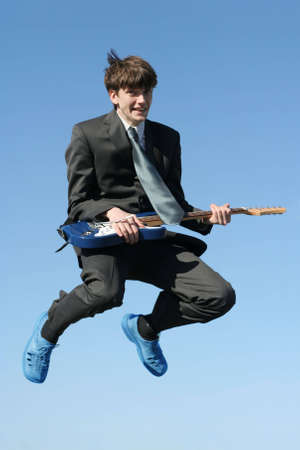 young happy businessman with guitar jumping highの写真素材