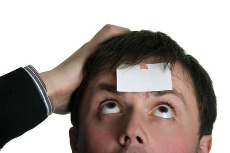 young man looking over the blank piece of paper on his foreheadの写真素材