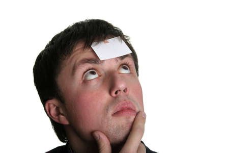 young man looking over the blank piece of paper on his foreheadの写真素材