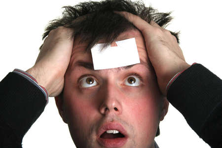 young man with crazy eyes and blank piece of paper on his foreheadの写真素材
