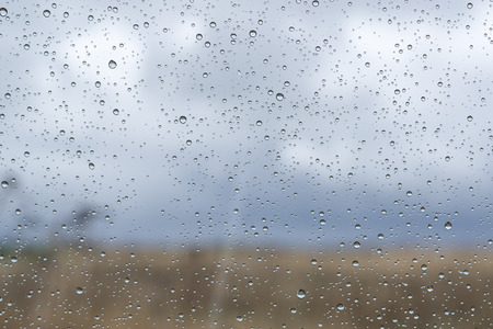 Window with rain drops on the glass outside natural landscape.