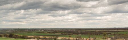 Panorama. Spring. Rural landscape with grey clouds over the fields and village.の写真素材