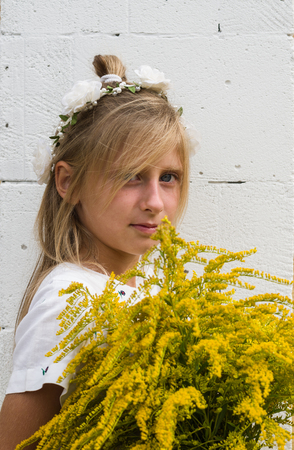 Girl with yellow flowers against the white wallの写真素材