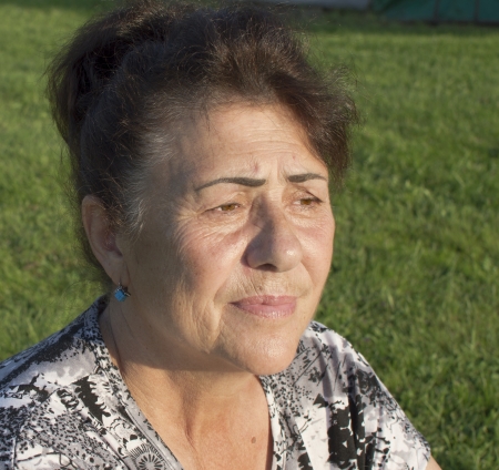 The elderly woman is photographed against a grass の写真素材