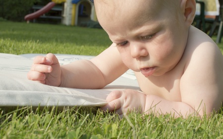 The baby lies on a grass and attentively studies it の写真素材
