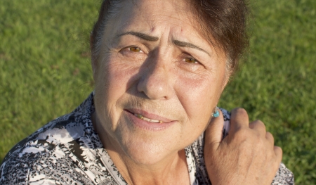 The elderly woman is photographed against a grass の写真素材