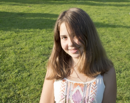 The girl of 13 years is photographed against a grass の写真素材