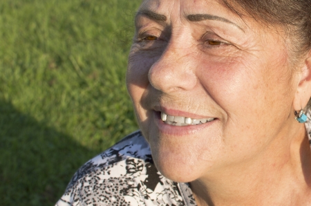 The elderly woman is photographed against a grass の写真素材