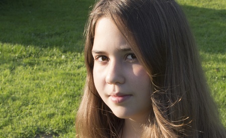 The girl of 13 years is photographed against a grass の写真素材