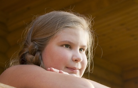 The girl is photographed on a balcony of the wooden house の写真素材