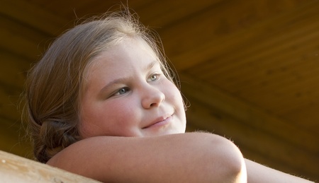 The girl is photographed on a balcony of the wooden house の写真素材