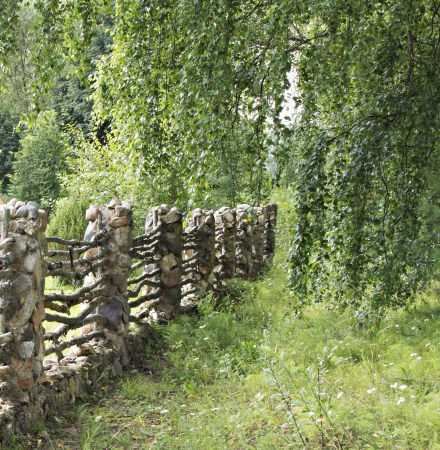 The old fence is made of a stone and a tree の写真素材