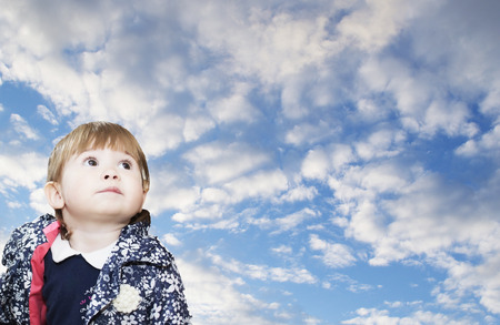 The girl of 1 year looks up against the blue sky.の写真素材
