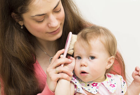 Mother is teaching the baby of 11 months old to brush hair の写真素材