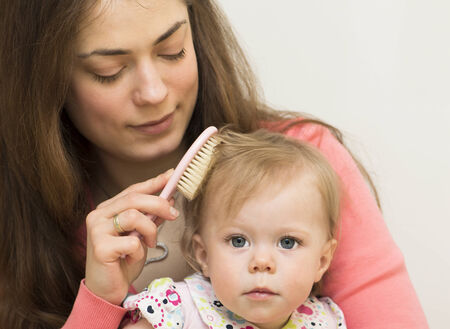 Mother is teaching the baby of 11 months old to brush hair の写真素材