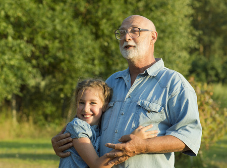 The grandfather is walking with granddaughter in a garden.の写真素材