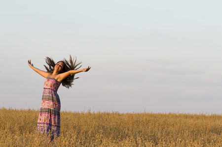 The beautiful girl is dancing in oat field.の写真素材