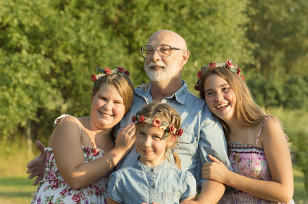 The grandfather is walking with granddaughters in a garden.の写真素材