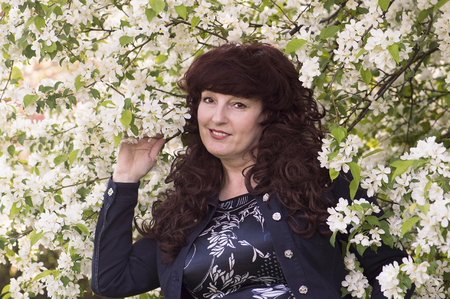 Outdoor portrait of the middle age woman beside a blossoming apple tree.の写真素材