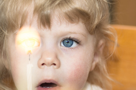 Little girl of 2 year old looking at a candle with her mouth wide open.の写真素材