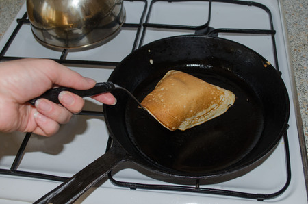 turning the roasting pancake on a gas stove on a cast iron skilletの写真素材