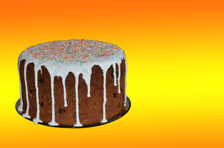 Easter cake with white icing and colored dressing on a yellow backgroundの写真素材