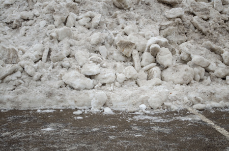 chipped ice from the asphalt road dumped in a pile on the side of the road