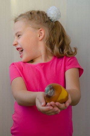 blonde girl with disgust abandons rotten pear shifted focusの写真素材