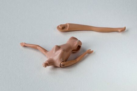 Broken headless doll with torn legs on a white background.の写真素材