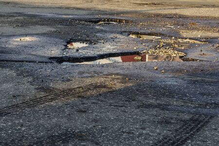 Road destroyed after winter. Puddles in the pits in the road