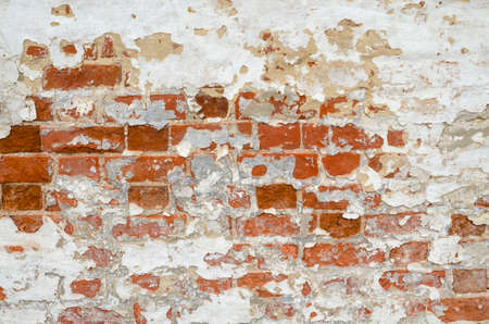 Background, texture of an old red brick wall with peeling white plasterの写真素材