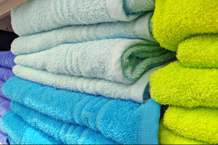 Stacks of colored bath towels on a shelfの写真素材