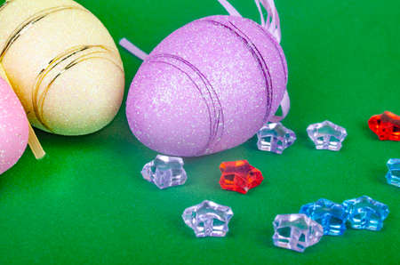 multi-colored Easter eggs with ribbons and colored pebbles on a green background