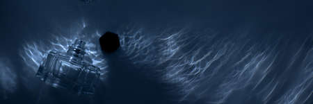 Perfume bottle with an open lid lies under water. Top view. Bannerの写真素材