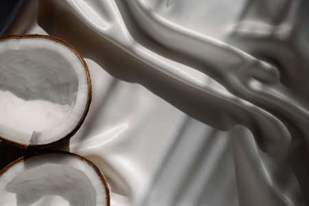 Two halves coconut on satin fabric under sunlight. Top viewの写真素材