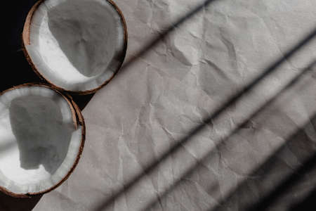 Two halves coconut on craft paper under sunlight. Top viewの写真素材